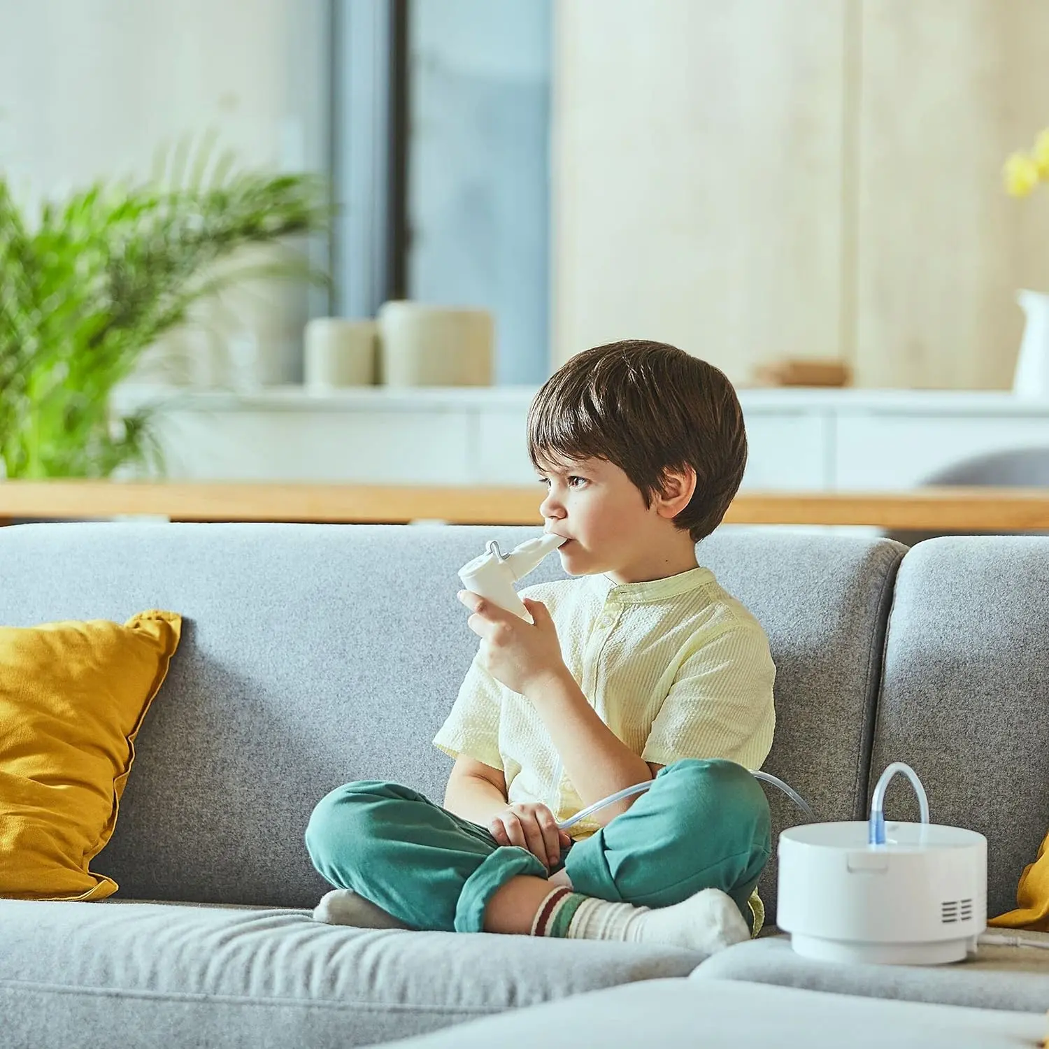 niño sentado en el sofá usando el nebulizador de la marca Omron tranquilamente